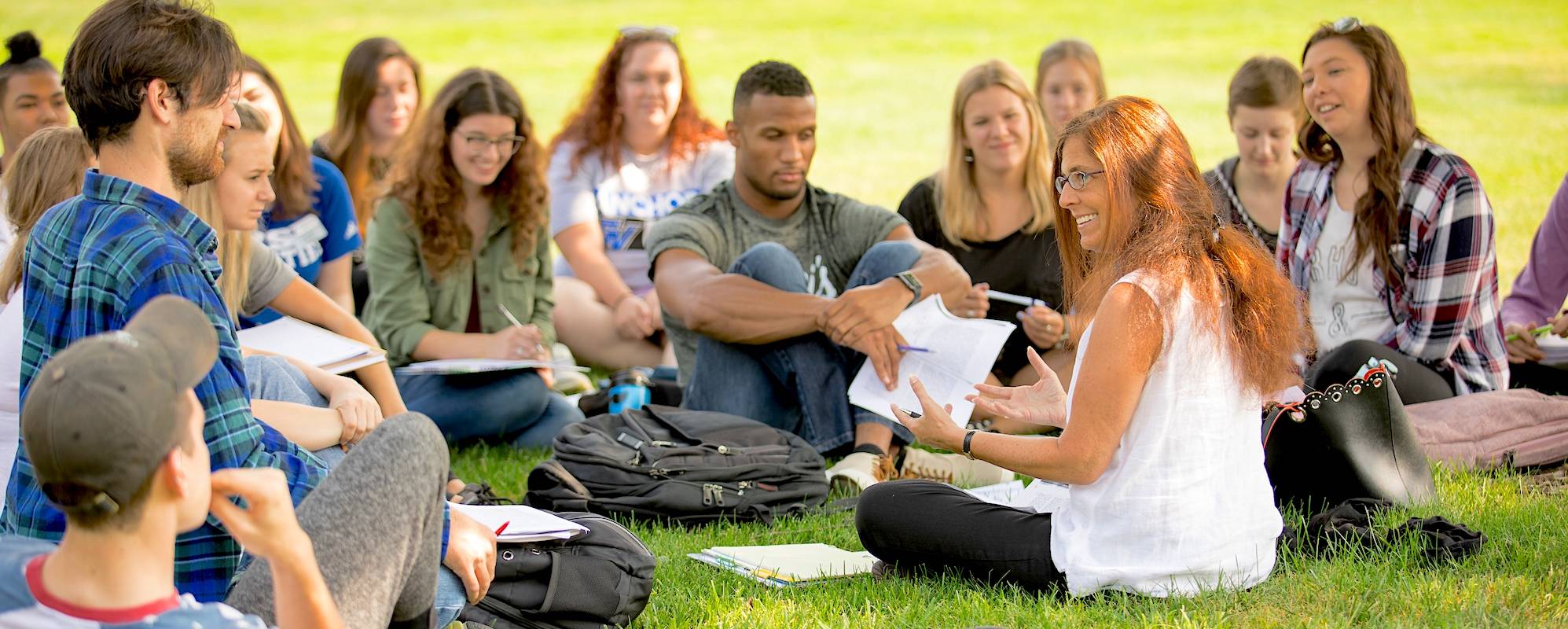 students sitting outside with professor